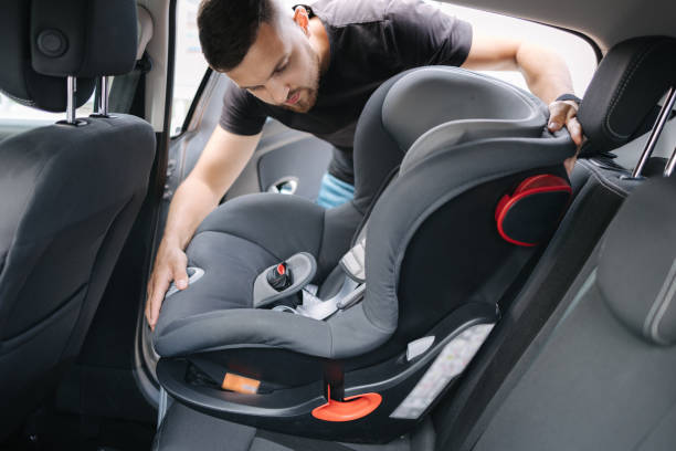 man installs a child car seat in car at the back seat. responsible father thought about the safety of his child - 嬰兒安全座椅 圖片 個照片及圖片檔