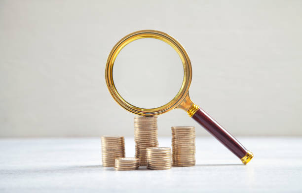 istock Magnifying glass and coins on the white desk. 1333329078