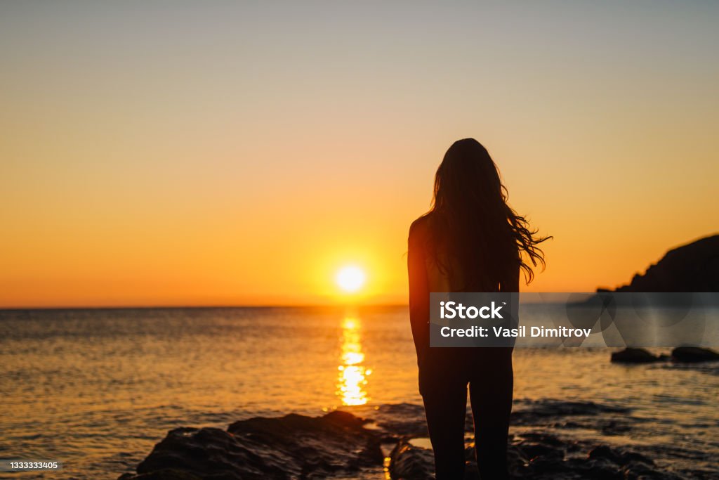 Breathe in, breathe out. Young woman enjoying the sunrise. Tranquility / Zen like photo. Calmness Contemplation Stock Photo