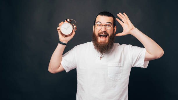 istock Dont be late, amazed man with beard and eyeglasses holding alarm clock 1333334568