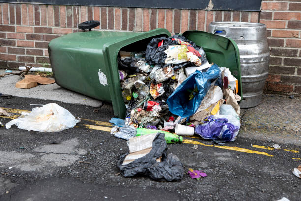 イングランド北部の都市の住宅裏通りにこぼれたゴミで転覆したウイリービン - garbage can garbage overflowing full ストックフォトと画像