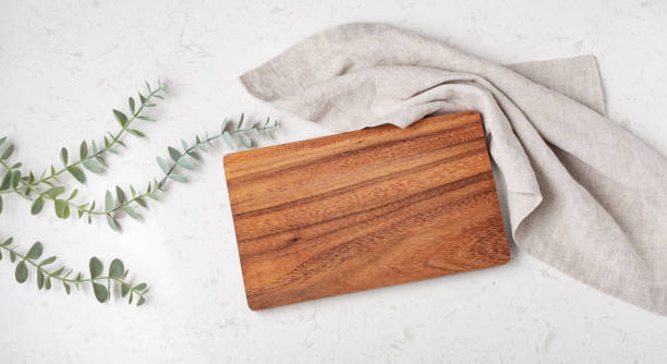 Wood cutting board with napkin and plant Wood cutting board with napkin on marble table, top view cutting board stock pictures, royalty-free photos & images