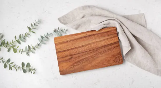 Wood cutting board with napkin on marble table, top view