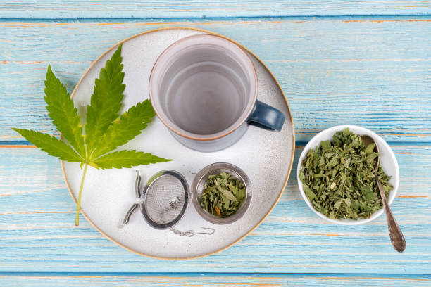 cannabis tea with cup and tea strainer - cannabis, marijuana - photography sign table ganja imagens e fotografias de stock