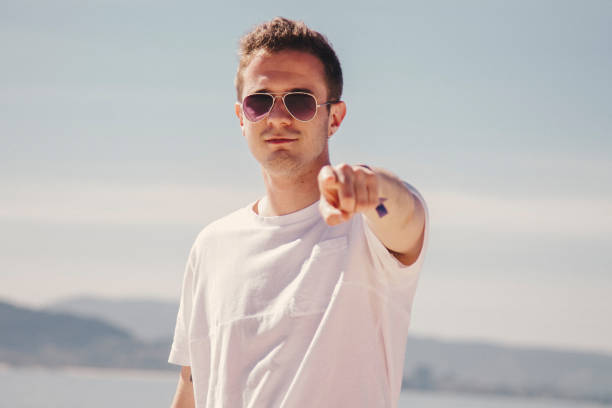 istock man with sunglasses walking on the beach and pointing a finger in a direction 1333341470