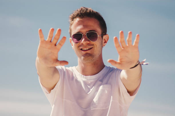 istock man in sunglasses walking on the beach and waving 1333341661