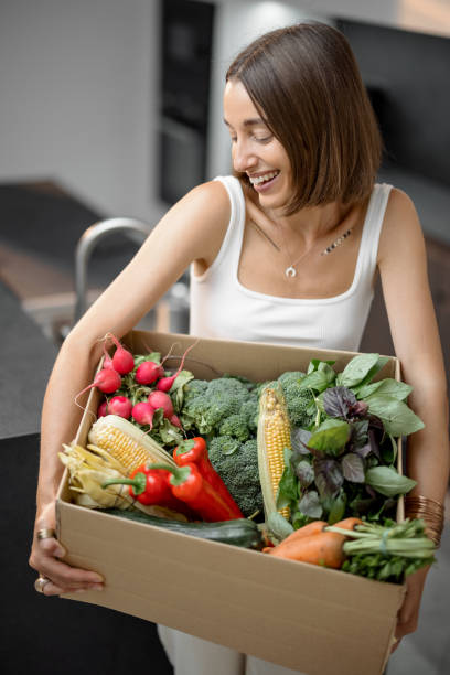 istock Woman with fresh vegetables packed in cardboard box at kitchen 1333345332