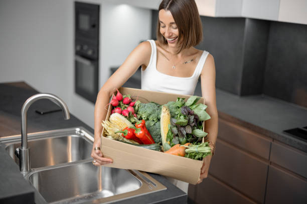 istock Woman with fresh vegetables packed in cardboard box at kitchen 1333345340