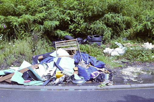 Street corner: debris on footpath. All junk. Tires, bed covers, plastic bags.