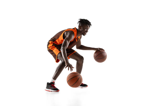 istock Young african man, basketball player in motion with two balls isolated over white studio background. Side view 1333346367
