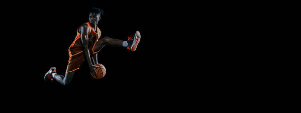istock Flyer. Young african man, basketball player practicing with ball isolated over dark studio background. 1333346376