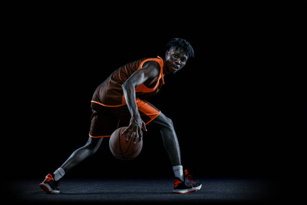 istock One young african man, basketball player practicing with ball isolated over dark studio background. 1333346387