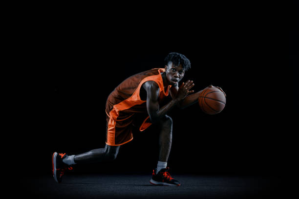 istock Professional african basketball player practicing with ball isolated over dark studio background. 1333346392