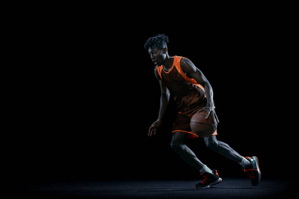 istock Professional african basketball player practicing with ball isolated over dark studio background. 1333346403