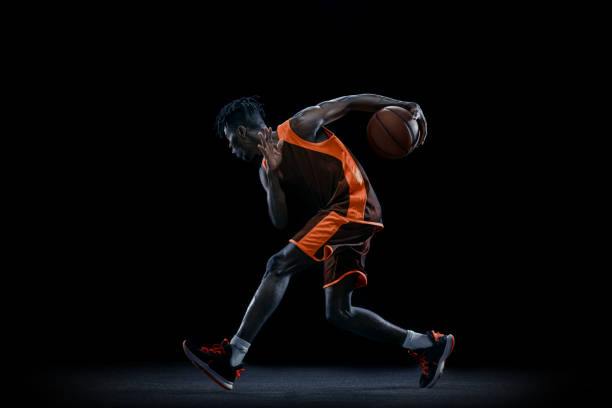istock Professional african basketball player practicing with ball isolated over dark studio background. 1333346406