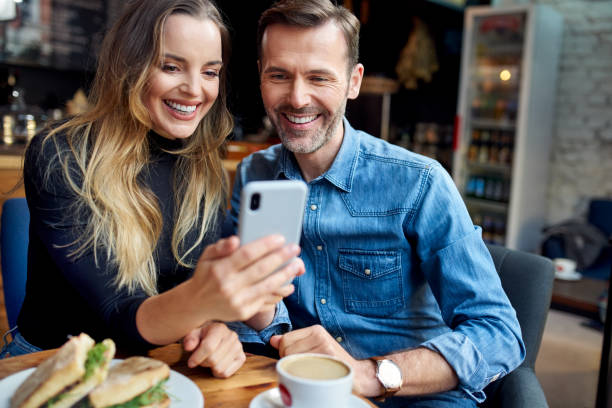 istock Relaxed couple in a cafe browsing smartphone together 1333346621