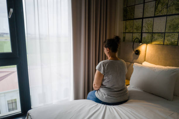 istock Woman sitting alone on bed in hotel room 1333348601