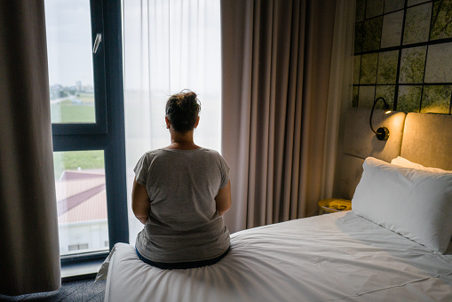 Mujer sentada sola en la cama en la habitación del hotel photo