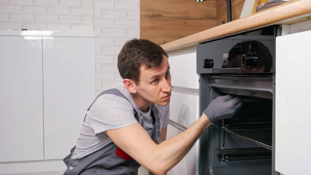 istock Skilled employee twists screw on broken oven repairing 1333349727