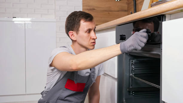 istock Man checks broken oven to repair siting on floor in kitchen 1333349729