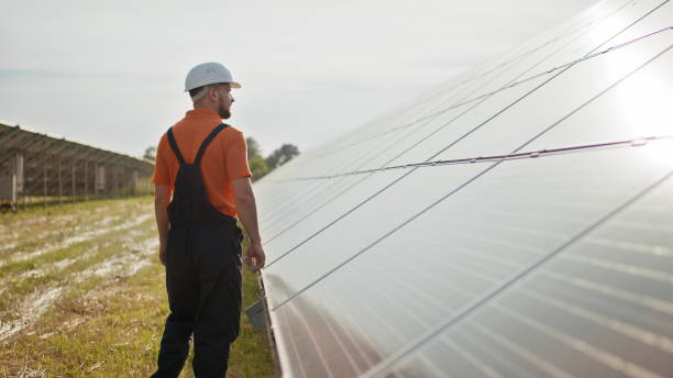 istock Professional male engineer in protective helmet walk on ecological solar plant construction. Concept of electricity, ecology, technologies. Farm of solar panels. Clean energy production. Green energy 1333349994