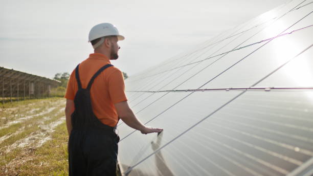 istock Professional male engineer in protective helmet walk on ecological solar plant construction. Concept of electricity, ecology, technologies. Farm of solar panels. Clean energy production. Green energy 1333350012