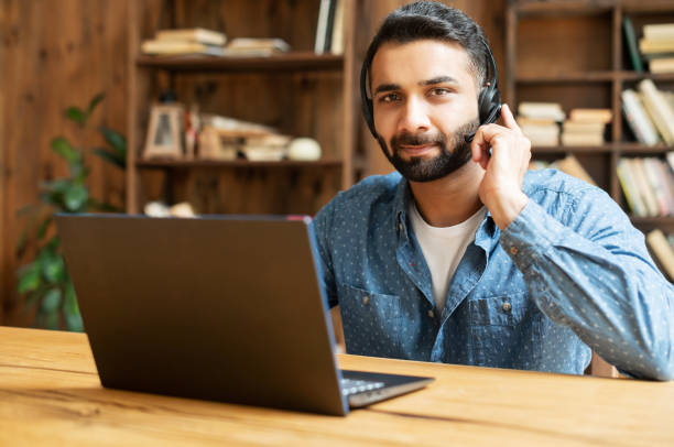 istock Portrait of confident Indian guy in wireless headset using laptop 1333350264