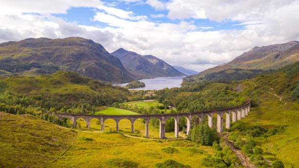 Glenfinnan Viaduct mit der West Highland Line in Glenfinnan in Schottland The Jacobite Steam Train is the Harry Potter Express (also called Hogwarts Express) from the Harry Potter film adaptations. The old steam locomotive runs here over the Glenfinnan Viaduct railway viaduct in Scotland. high country stock pictures, royalty-free photos & images