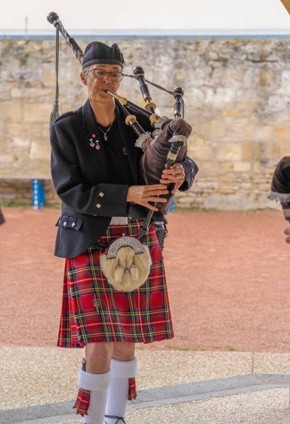 Langrune-Sur-Mer, France - 08 05 2021: Auld Alliance Pipe Band Langrune-Sur-Mer, France - 08 05 2021: Auld Alliance Pipe Band: Detail of the costume and instrument of a bagpiper tank musician stock pictures, royalty-free photos & images