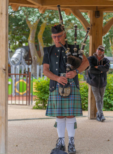 Langrune-Sur-Mer, France - 08 05 2021: Auld Alliance Pipe Band Langrune-Sur-Mer, France - 08 05 2021: Auld Alliance Pipe Band: Detail of the costume and instrument of a bagpiper tank musician stock pictures, royalty-free photos & images