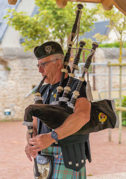 Langrune-Sur-Mer, France - 08 05 2021: Auld Alliance Pipe Band Langrune-Sur-Mer, France - 08 05 2021: Auld Alliance Pipe Band: Detail of the costume and instrument of a bagpiper tank musician stock pictures, royalty-free photos & images