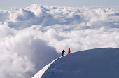 Mountaineers passing a mountain ridge high above the clouds