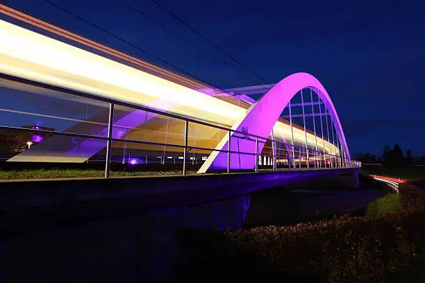 A light rail is passing an illuminated bridge near Stuttgart / Germany