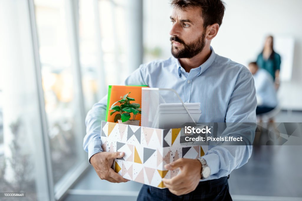 Leaving the office Business, Firing and Job Loss Concept - Sad Fired Male Office Worker With Box of His Personal Stuff Quitting a Job Stock Photo