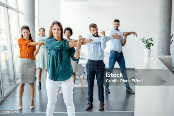 Businesspeople Doing Stretching Exercise At Workplace Stock Photo - Download Image Now