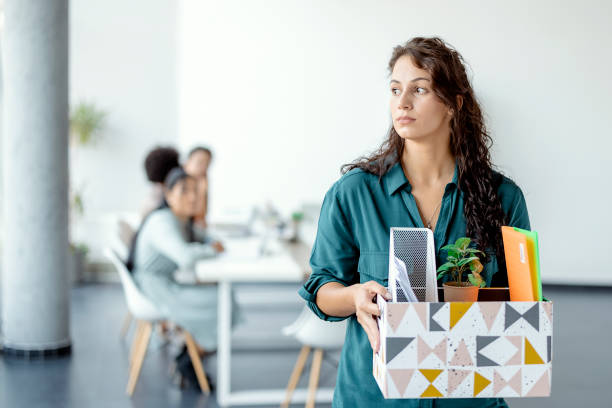 Woman Getting Fired From Work Portrait of young beautiful woman employee getting fired from work. Female walks through the office, carrying box with personal belongings. Business, firing and job loss concept being fired photos stock pictures, royalty-free photos & images