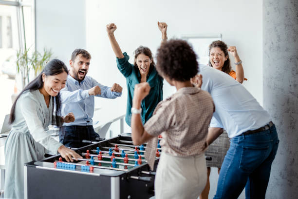 compañeros de trabajo jugando al futbolín - break office 30s 20s fotografías e imágenes de stock