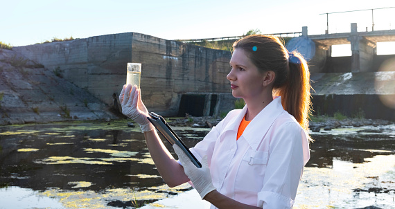a female ecologist takes water samples for contamination, the concept of ecology. High quality photo
