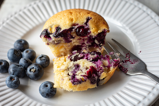 blueberry cupcake cut to eat on a white plate