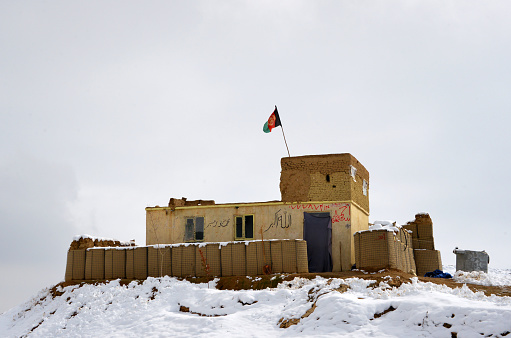 Takht-i Rustam, Haibak, Samangan Province: Afghan National Army (ANA) defensive position - fortified outpost on a snow covered hill top near Haibak - flag of Afghanistan.