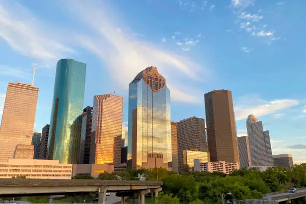 Downtown Houston Skyscraper buildings at sunset with view of cars on freeway in front. Texas, USA.