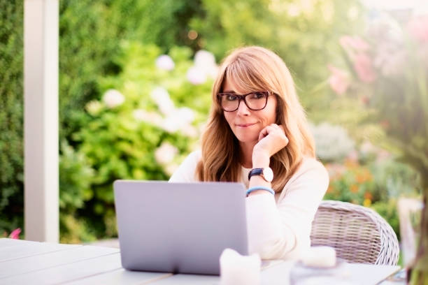 istock Attractive mature woman using laptop while sitting in the backyard at home 1333371080