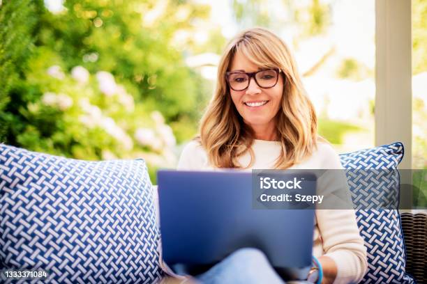 Attractive Mature Woman Using Laptop And Having Video Call While Sitting In The Backyard At Home Stock Photo - Download Image Now