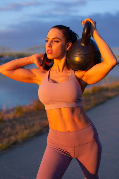 istock Young woman holding kettlebell on shoulder at riverbank 1333374486