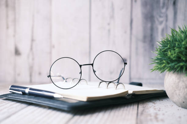 istock notepad, eyeglass and a pencil on wooden table 1333377446