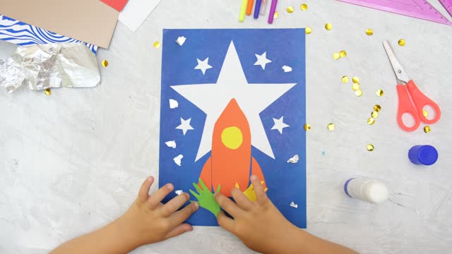 Child making rocket and stars from paper. Creative children play with craft. The space theme development of children.  School education handmade creativity.
