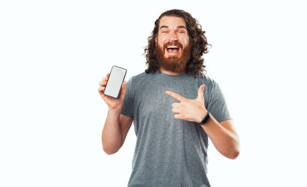 istock Amazed bearded hipster man pointing at smartphone screen over white background 1333386728