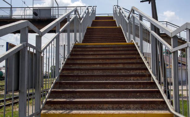 istock Railway bridge with steps, with impressive steps in perspective. Overhead pedestrian crossing. Bridge stairs connecting one platform to another at the train station 1333386808
