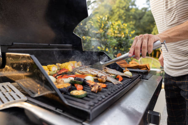 grigliare pesce e mais su una griglia - barbecue foto e immagini stock