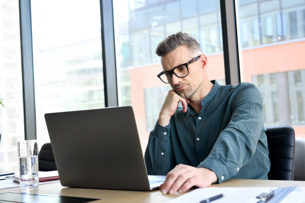 istock Focused middle aged businessman thinking using laptop sitting at office table. 1333390942